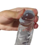 Dildo realist transparent din TPE, prim-plan cu glandul ținut între degete