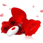 Dop anal Rose roșu, cu telecomanda wireless alături, între petale de trandafir
