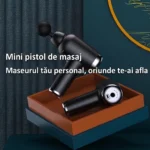 Două mini pistoale de masaj negre într-o tavă maro, unul cu panoul din spate cu buton, port de încărcare și șase puncte