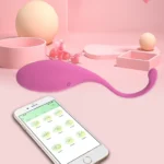 Oul vibrator roz așezat pe un decor pastel, cu telefonul și aplicația deschisă în față